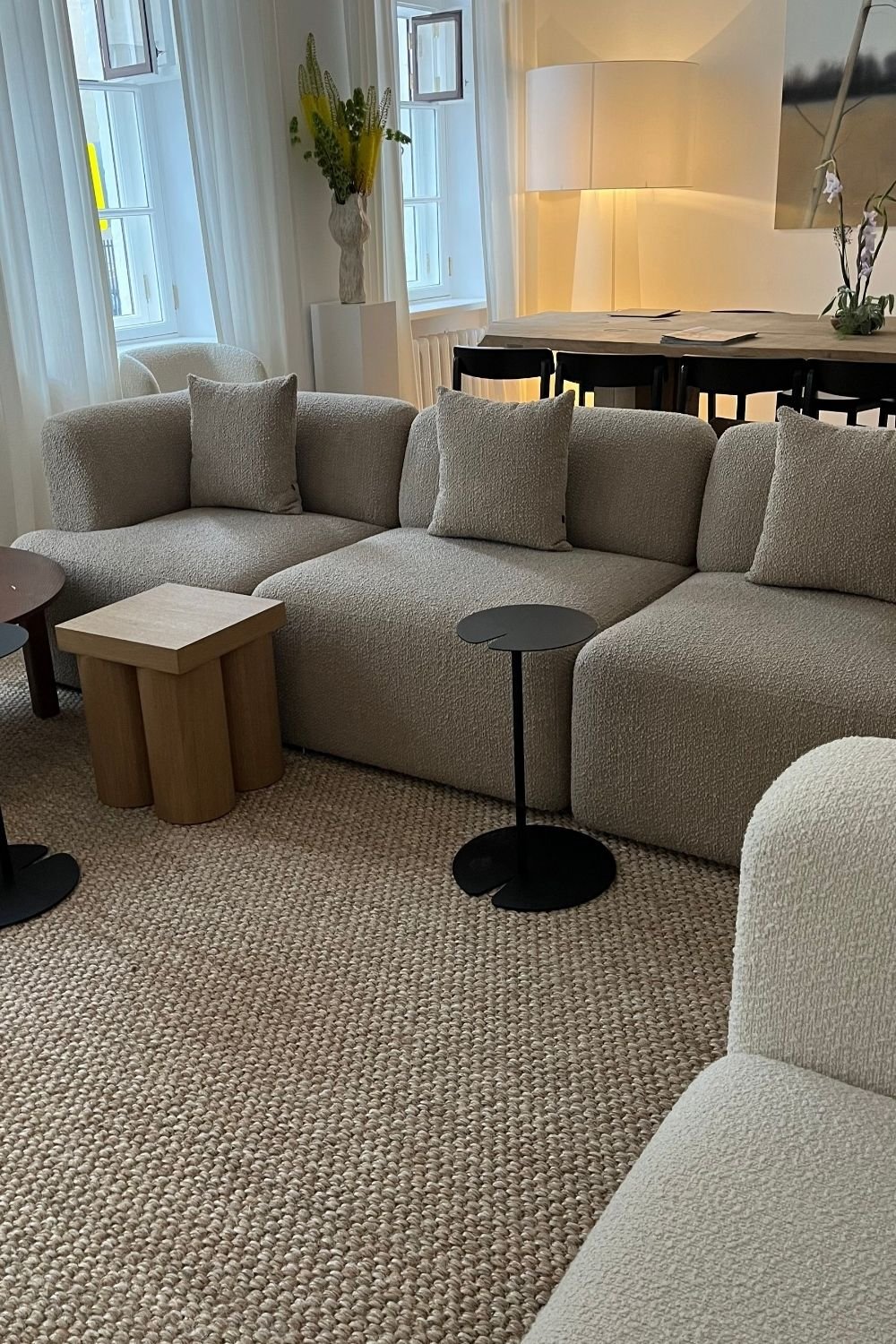 Modular boucle sofa pieces in a row with small side tables on a chunky jute rug