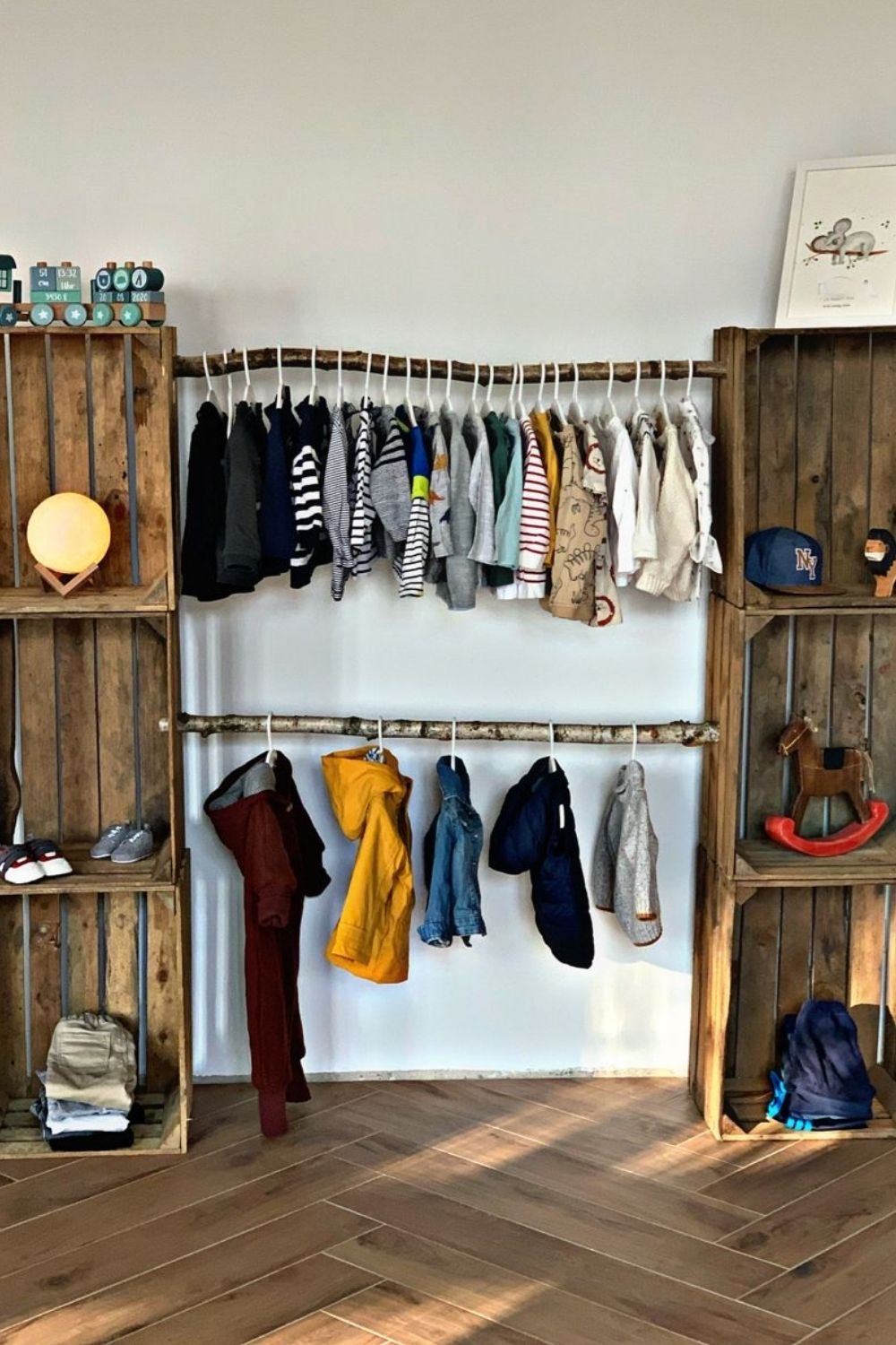 Two birch branch rails mounted on a white wall in a child's room, with wooden crates used as shelving