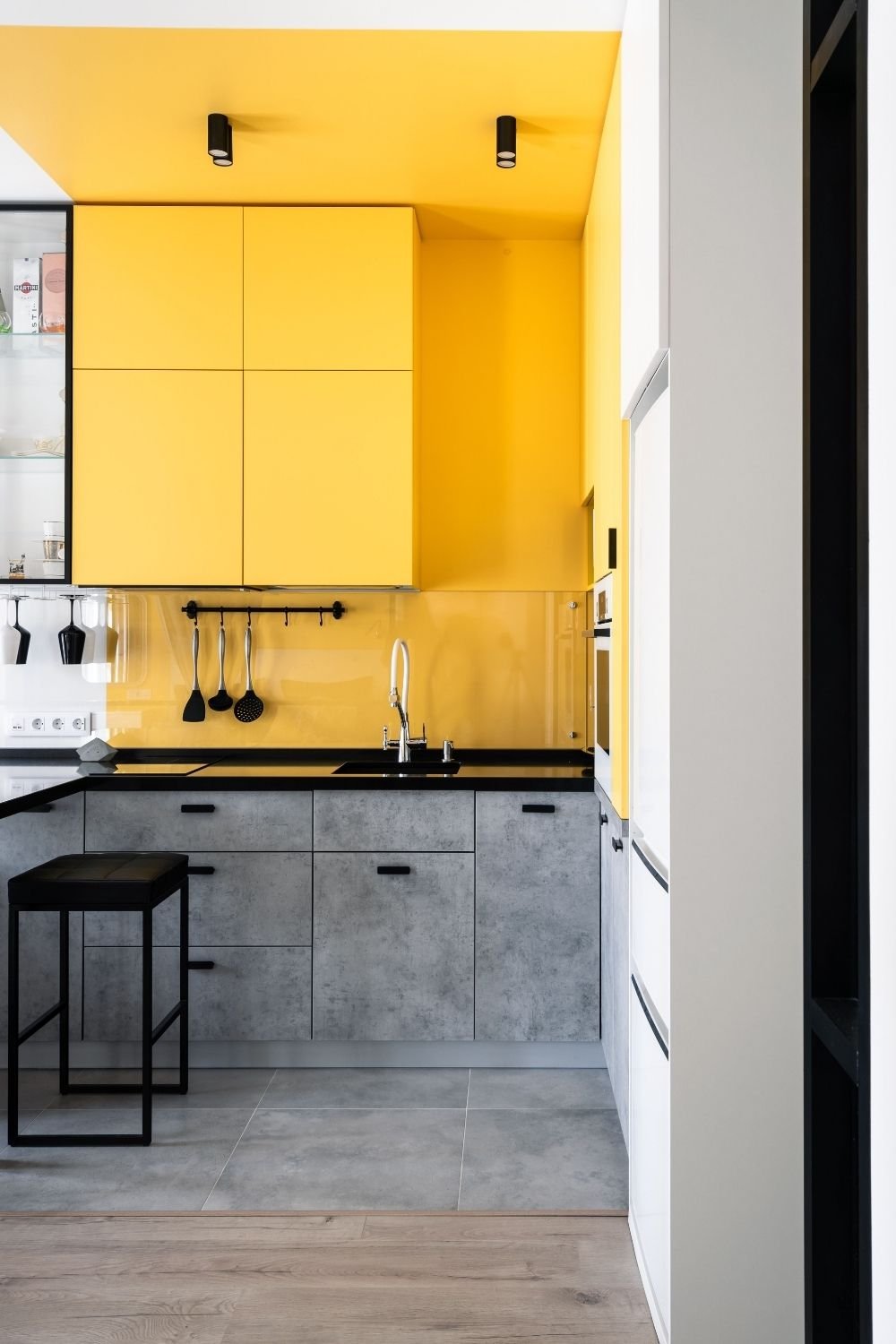 Small galley kitchen with bright yellow upper cabinets and ceiling above concrete gray base units