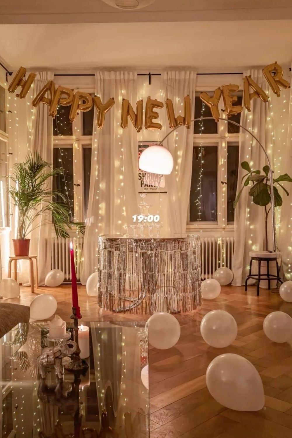 Gold Happy New Year balloon letters above a silver fringed drinks table with a stacked champagne tower
