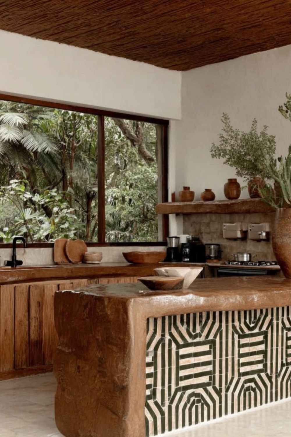 Kitchen with a hewn timber island faced in green and cream geometric tile, terracotta pots and a reed ceiling