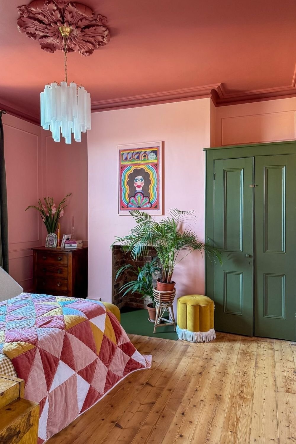 Pink bedroom with a terracotta ceiling and cornice, green painted cupboard doors and a patchwork velvet quilt